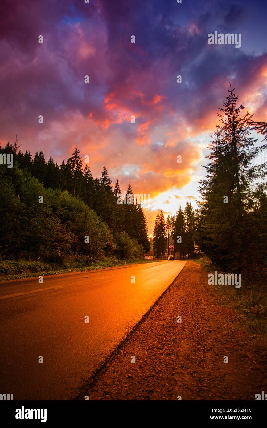 Tramonto su una vuota autostrada di montagna circondata da boschi Foto Stock