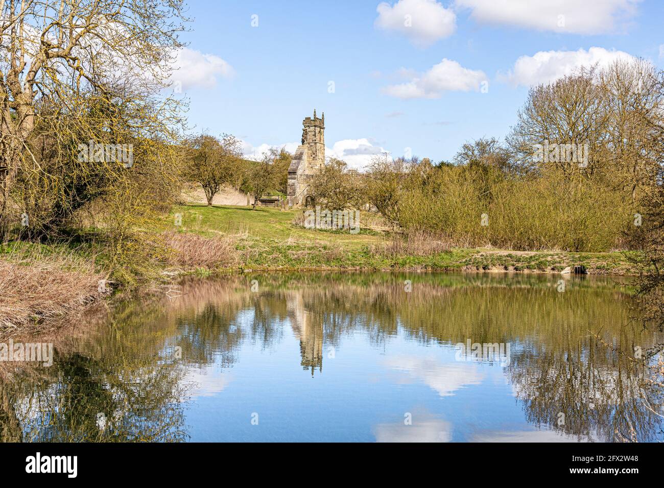 Le rovine della chiesa di St Martins si sono riflesse in un laghetto di mulino abbandonato a Wharram Percy deserted Medieval Village sul Yorkshire Wolds, North Yorkshire, Foto Stock