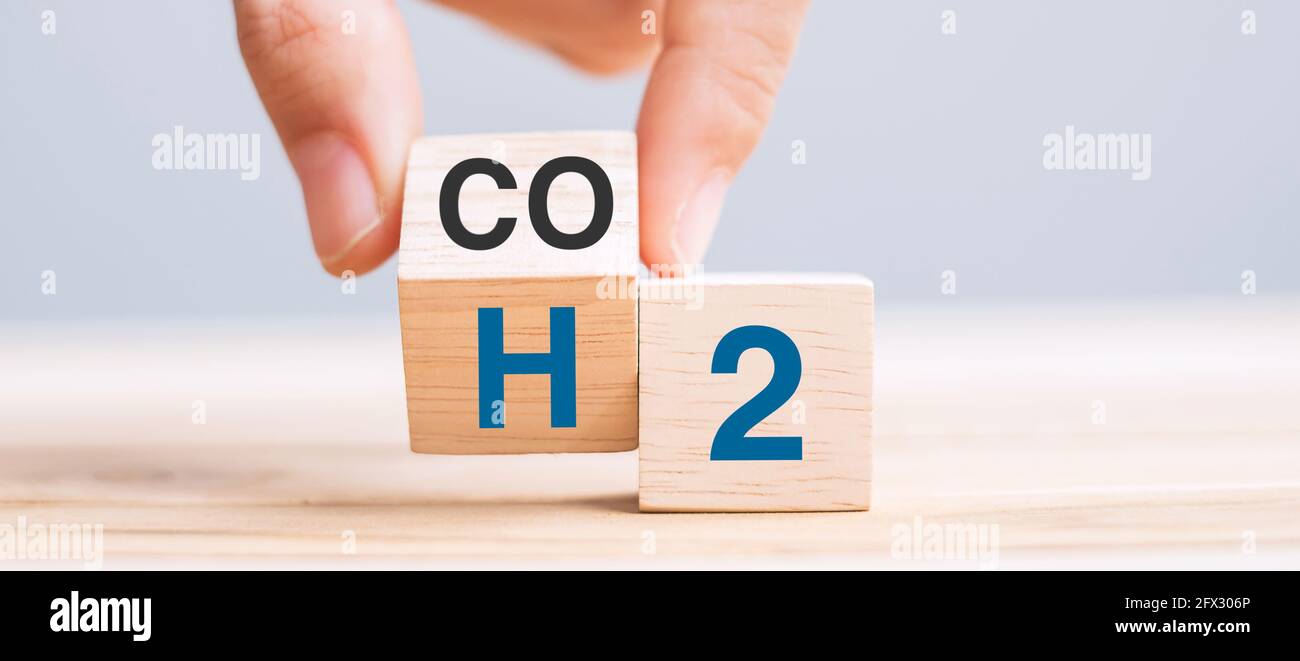 Capovolgere manualmente i blocchi cubici di legno con CO2 (anidride carbonica), cambiare in H2 (idrogeno) testo sullo sfondo della tabella. Carbonio libero, energia alternativa e globo Foto Stock