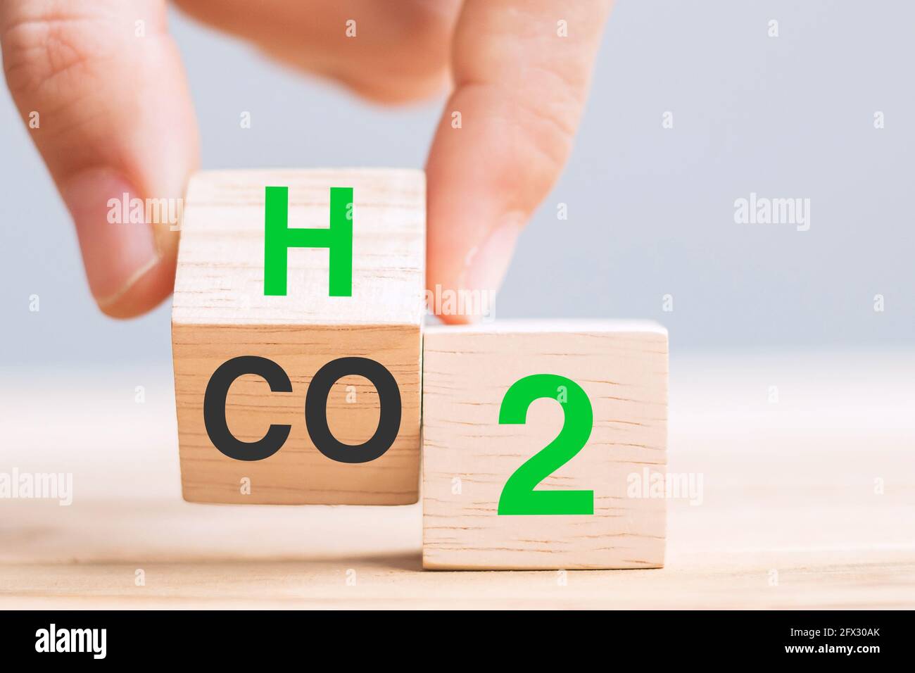 Capovolgere manualmente i blocchi cubici di legno con CO2 (anidride carbonica), cambiare in H2 (idrogeno) testo sullo sfondo della tabella. Carbonio libero, energia alternativa e globo Foto Stock