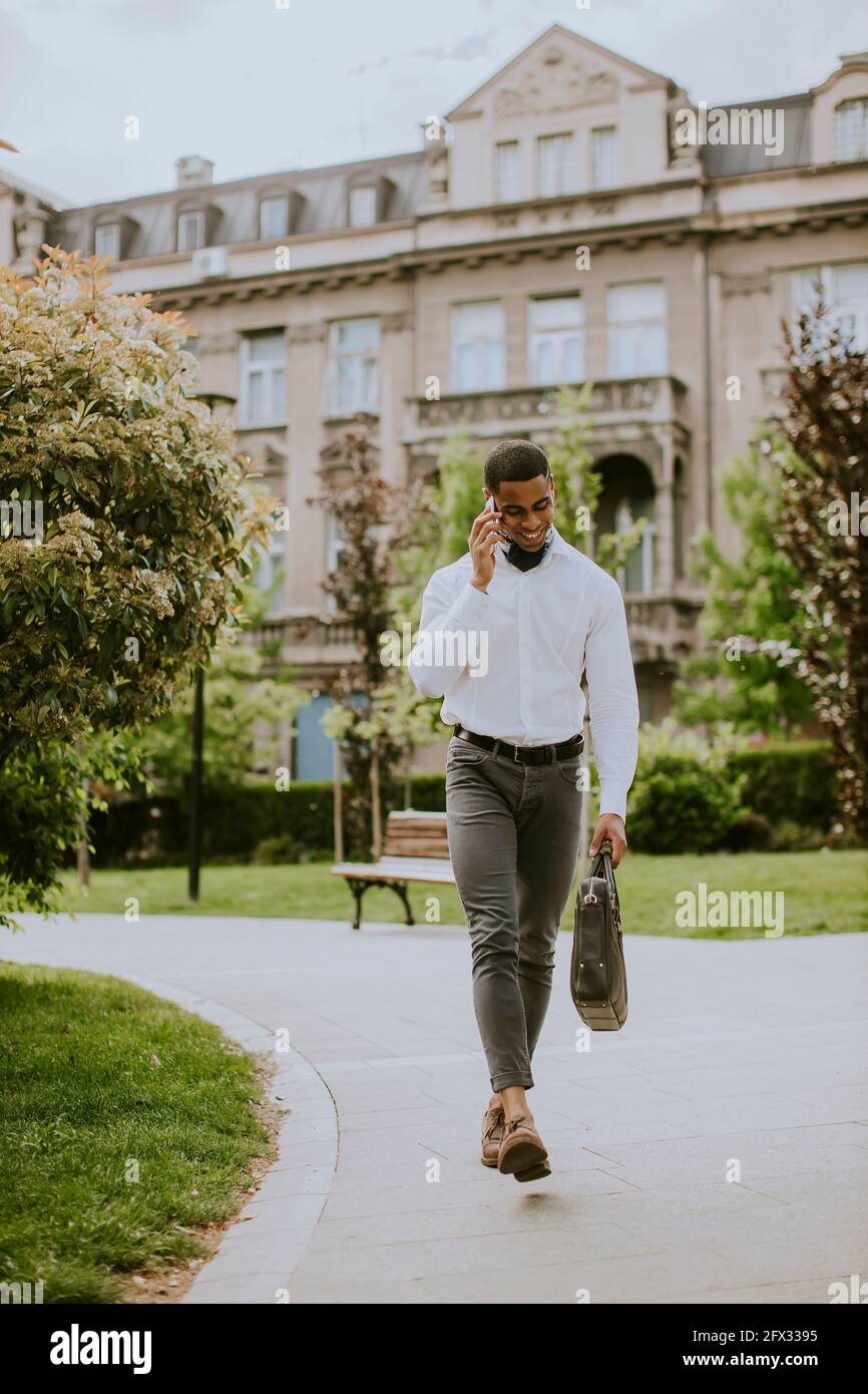Bel giovane uomo d'affari afro-americano che usa un cellulare su una strada Foto Stock