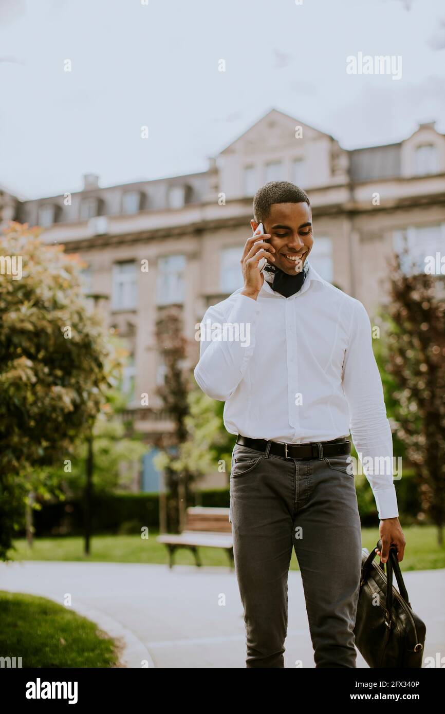 Bel giovane uomo d'affari afro-americano che usa un cellulare su una strada Foto Stock