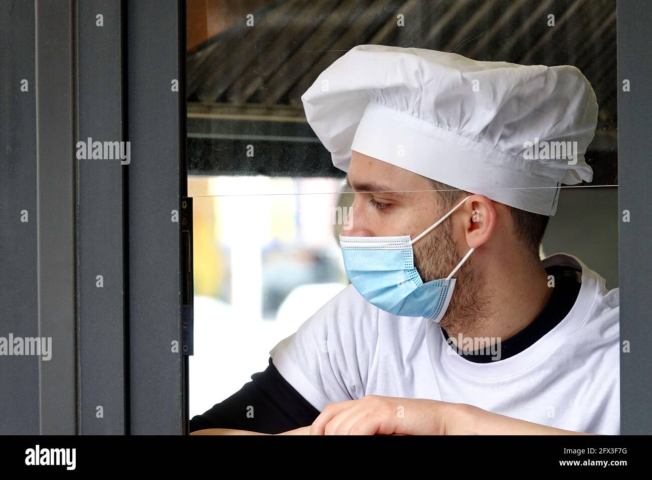 Un giovane chef che indossa una maschera covid durante una pausa di lavoro. Milano, Italia - Maggio 2021 Foto Stock
