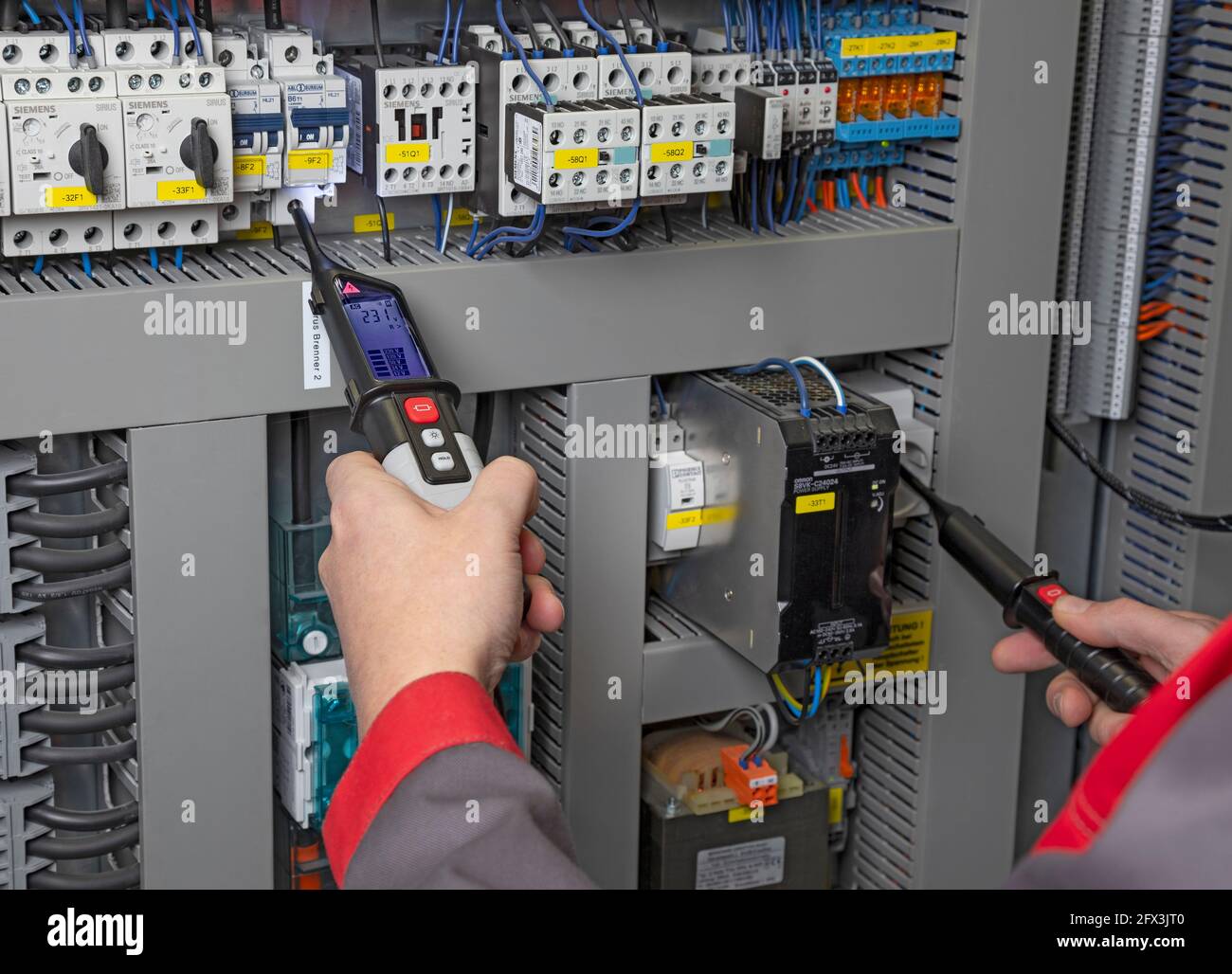 elettricista che esegue la misurazione con un multimetro all'interno di un armadio elettrico Foto Stock