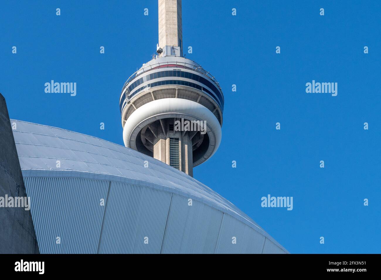 La CN Tower in una bella giornata cielo blu a Toronto, Canada. Il simbolo canadese è incorniciato nell'architettura del Rogers Centre Foto Stock