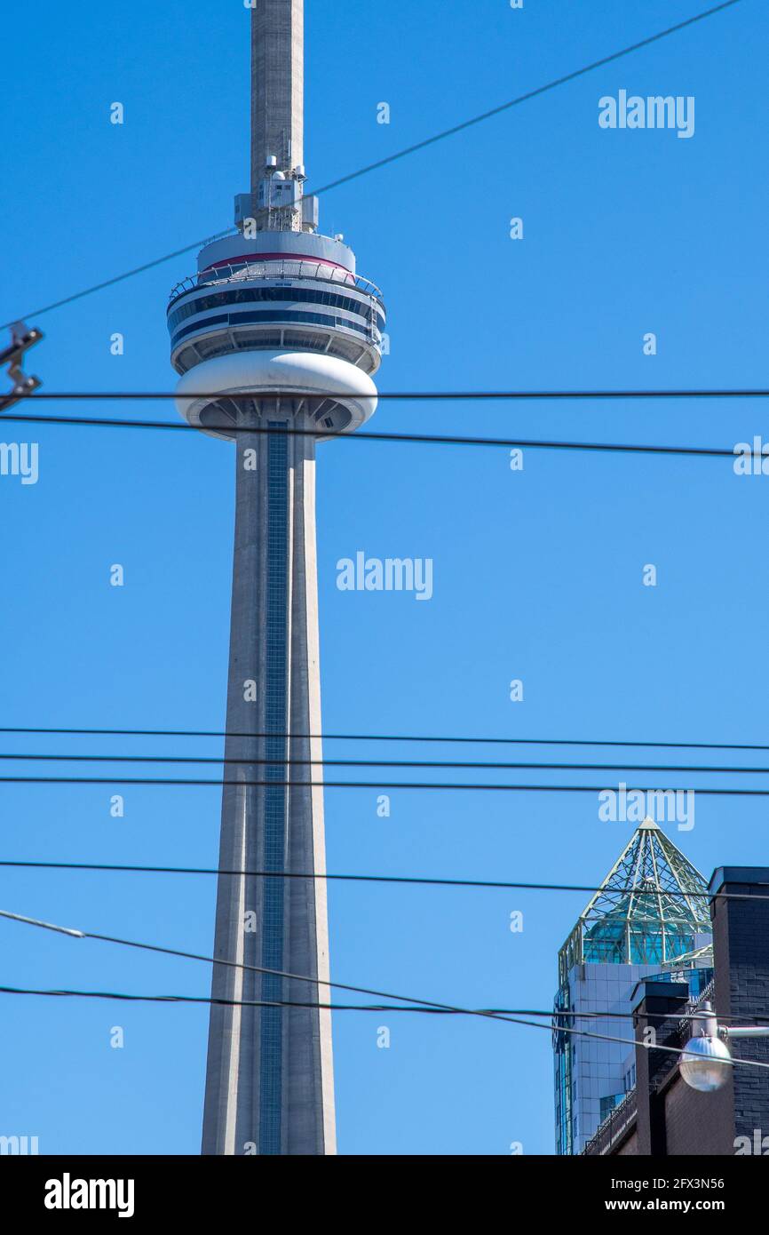 La CN Tower in una bella giornata cielo blu a Toronto, Canada. Il simbolo canadese è incorniciato da cavi elettrici per auto Foto Stock