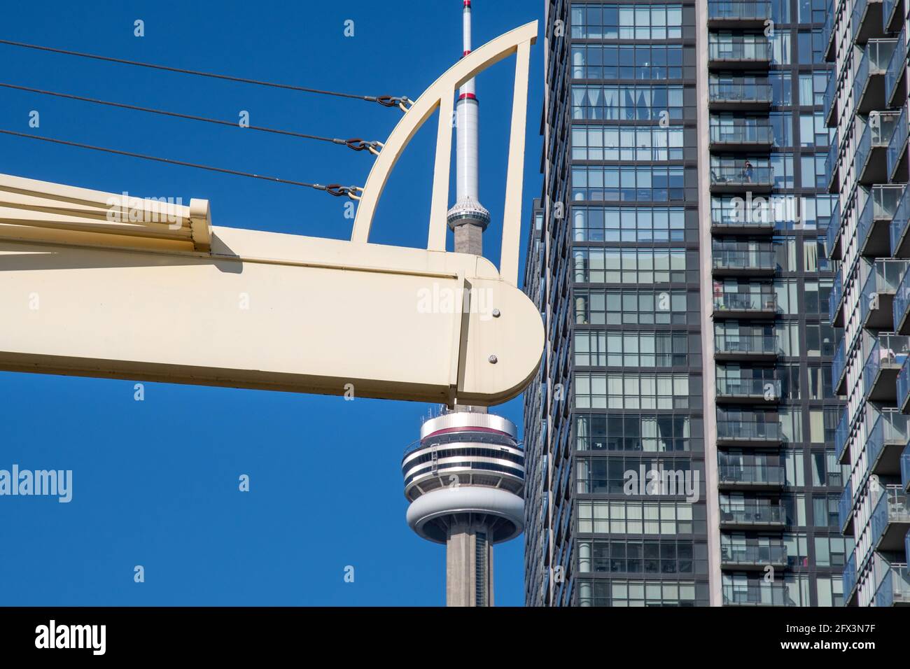La CN Tower in una bella giornata cielo blu a Toronto, Canada. Il simbolo canadese è incorniciato dal ponte pedonale CityPlace e dai grattacieli. Foto Stock