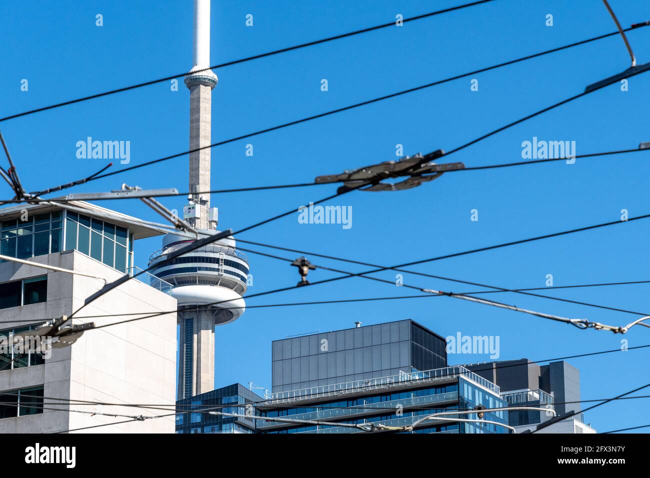 La CN Tower in una bella giornata cielo blu a Toronto, Canada. Il simbolo canadese è incorniciato da cavi elettrici per auto Foto Stock