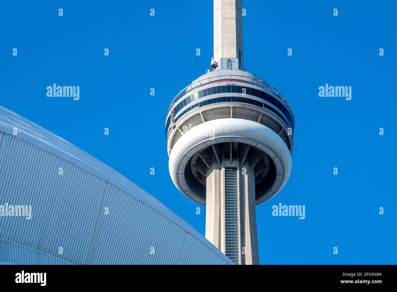 La CN Tower in una bella giornata cielo blu a Toronto, Canada. Il simbolo canadese è incorniciato nell'architettura del Rogers Centre Foto Stock