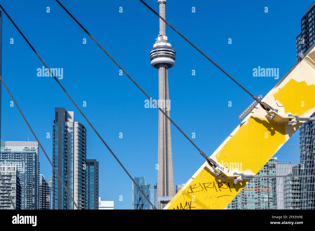 La CN Tower in una bella giornata cielo blu a Toronto, Canada. Il simbolo canadese è incorniciato dal ponte pedonale CityPlace. Foto Stock