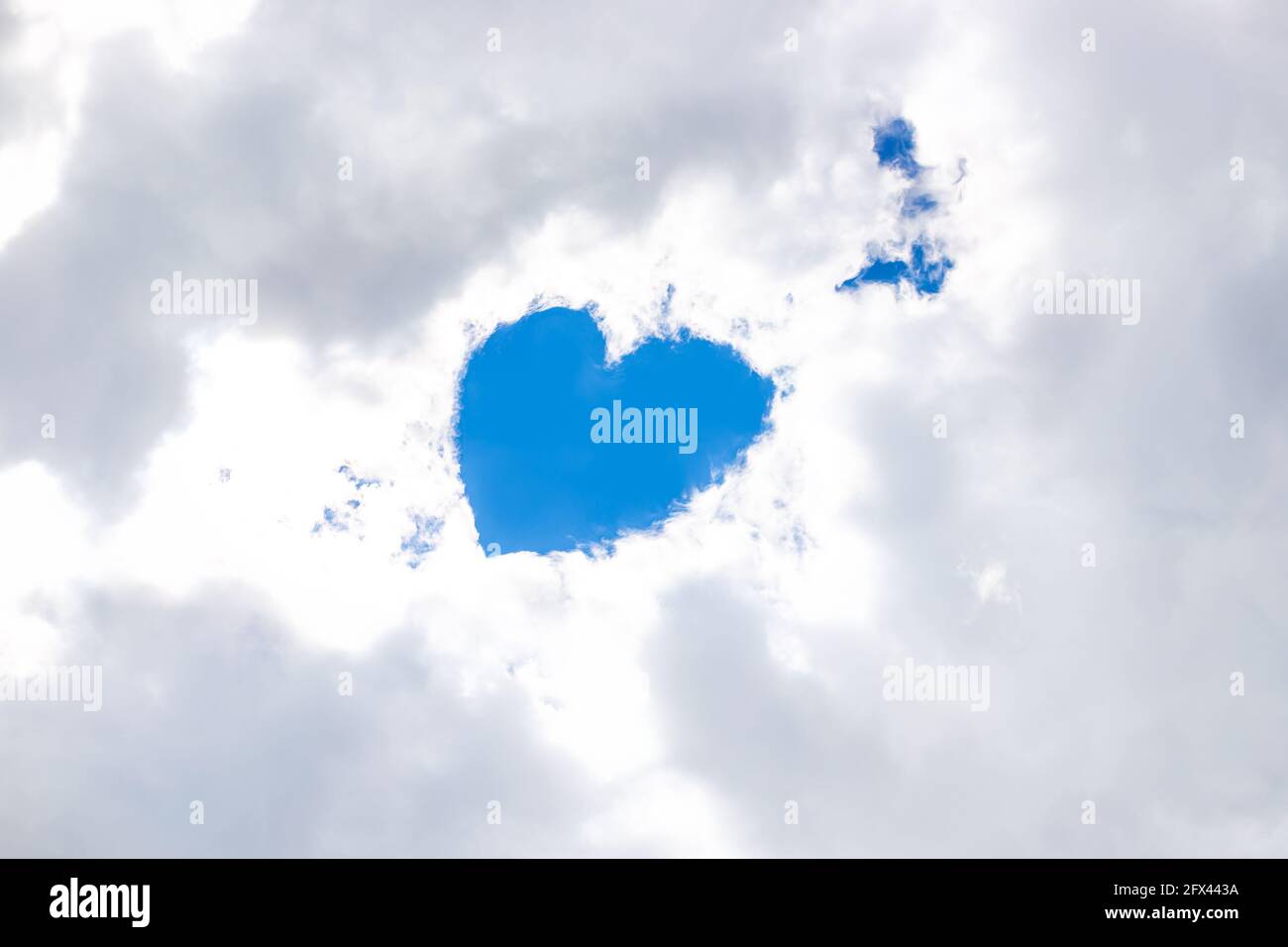 Nelle nubi bianche della neve nel gap c'è un cuore dal cielo blu, un angelo è nelle vicinanze. Inserire il testo. Concetto di amore, dio, adempimento dei desideri. Foto Stock