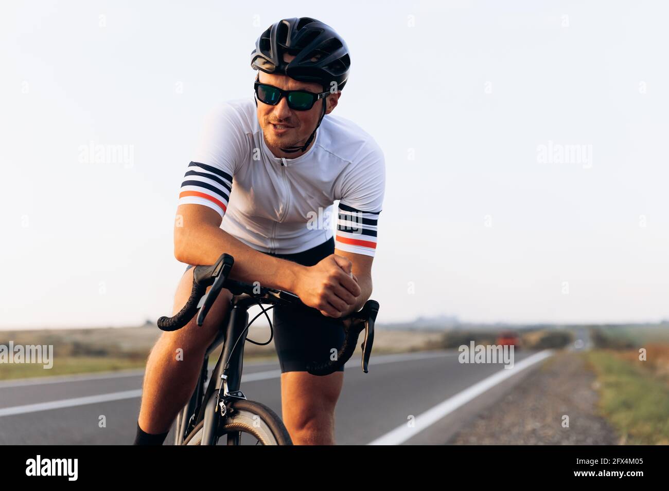 Ciclista sorridente seduto in bicicletta all'aperto Foto Stock