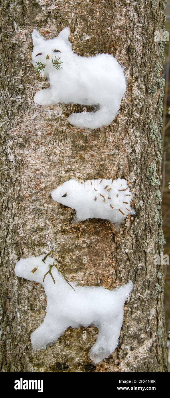 Approccio creativo per i bambini. I bambini hanno bloccato una figura di neve di un hedgehog e renna settentrionale e gatto su un albero (come un alto rilievo) Foto Stock