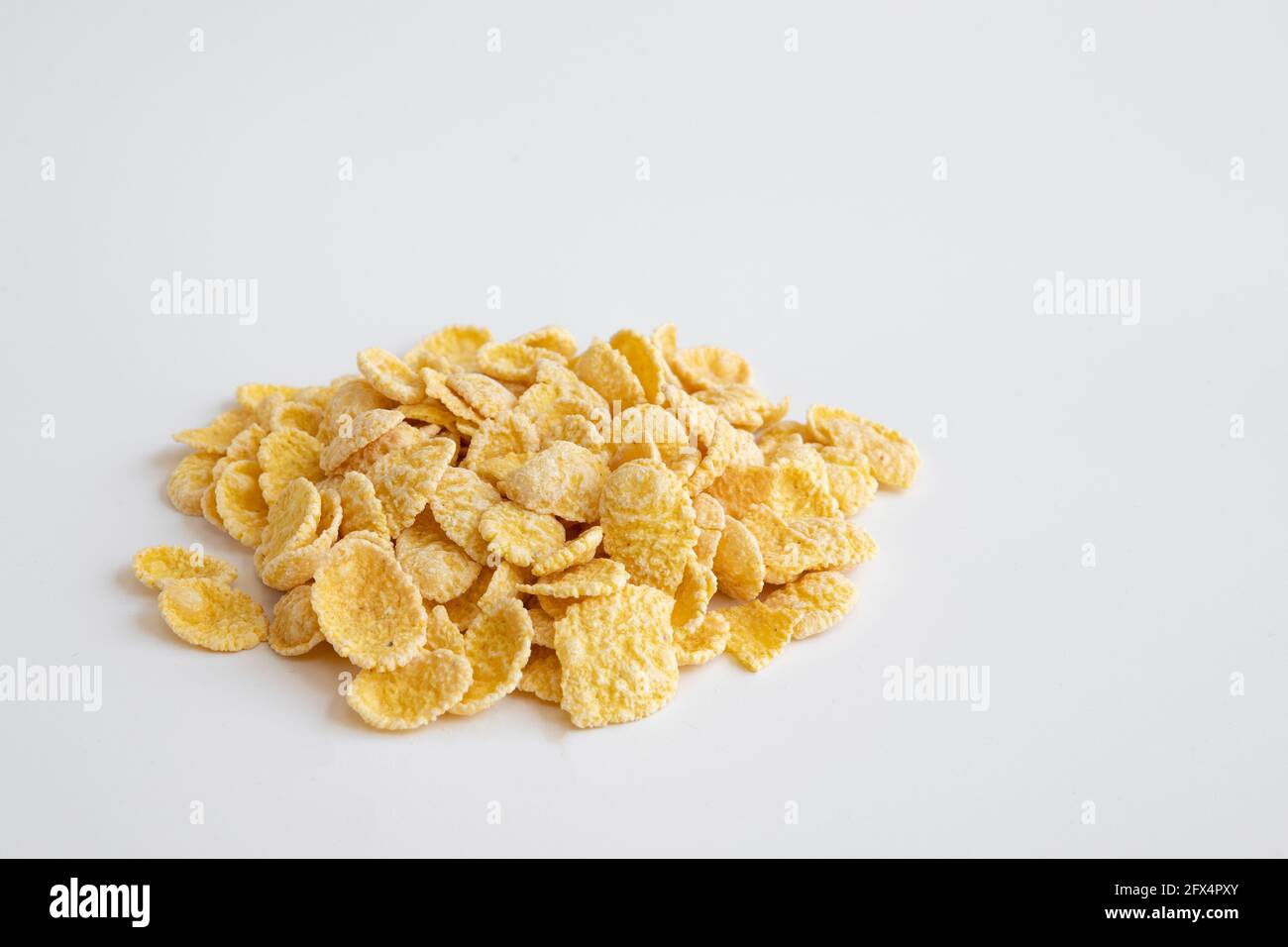 fiocchi di mais isolati su sfondo bianco, ingredienti alimentari, cereali di mais gialli per colazione, mucchio di fiocchi di mais ricoperti di zucchero tagliati, vista laterale Foto Stock