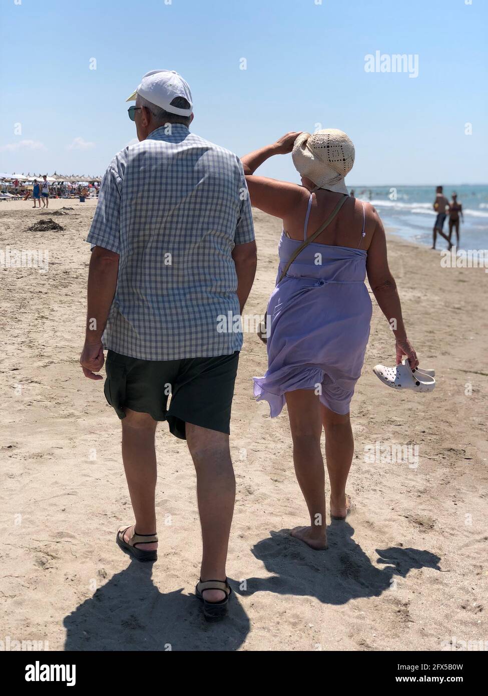 Vista posteriore di una coppia felice senior a piedi sulla spiaggia adriatica. Foto Stock