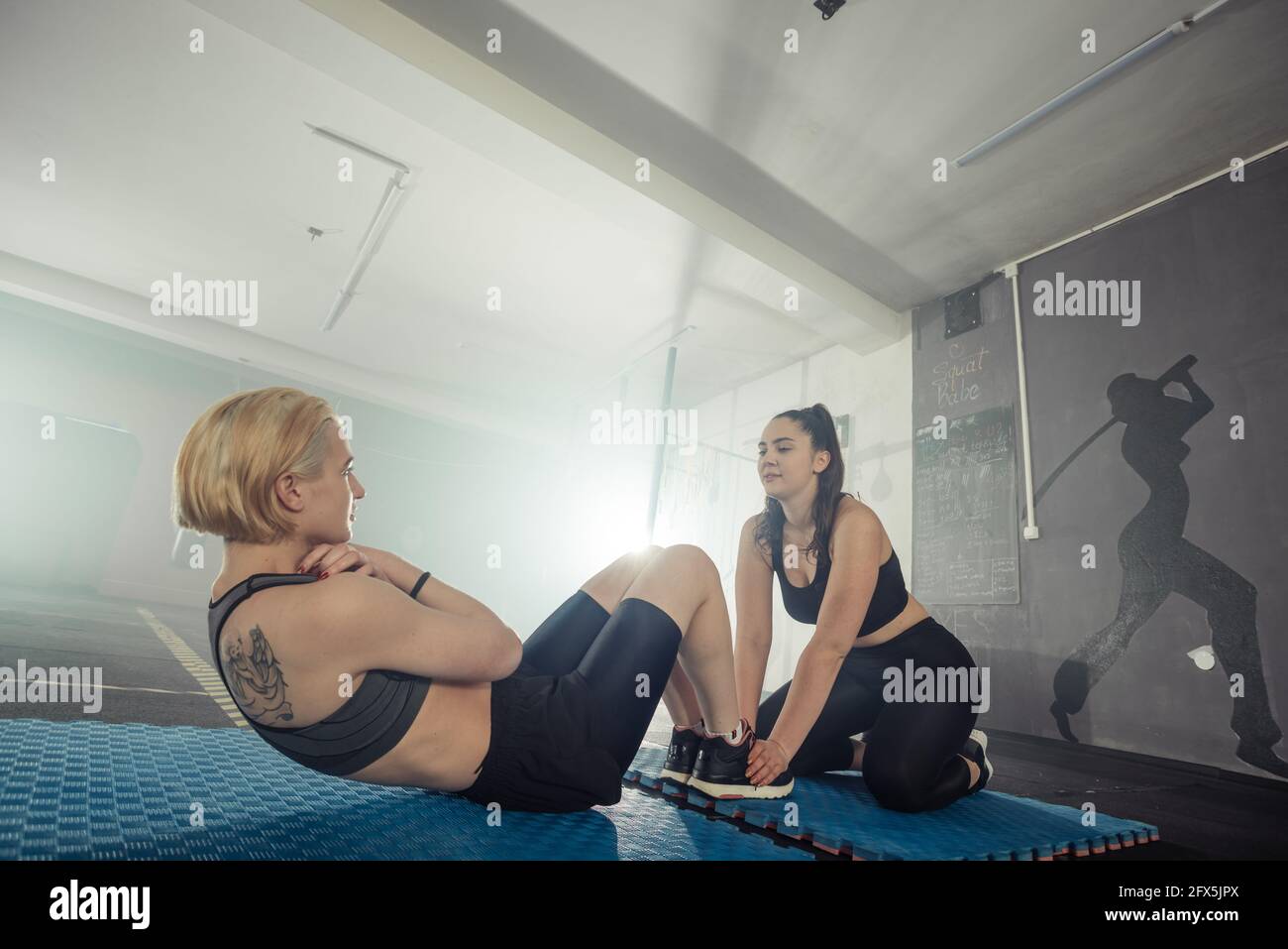 Donne in bianco e nero abbigliamento sportivo su un vero gruppo corpo combattimento allenamento in palestra treno per combattere, kickboxing con un allenatore. Foto Stock