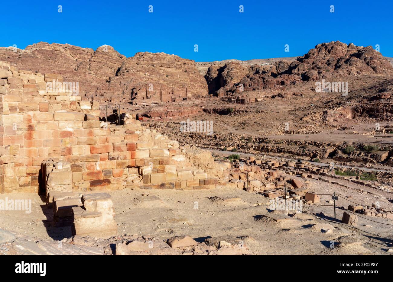 Parete parzialmente ricostruita del tempio dei leoni alati, con tombe sullo sfondo presso il sito archeologico storico di Petra, Giordania Foto Stock