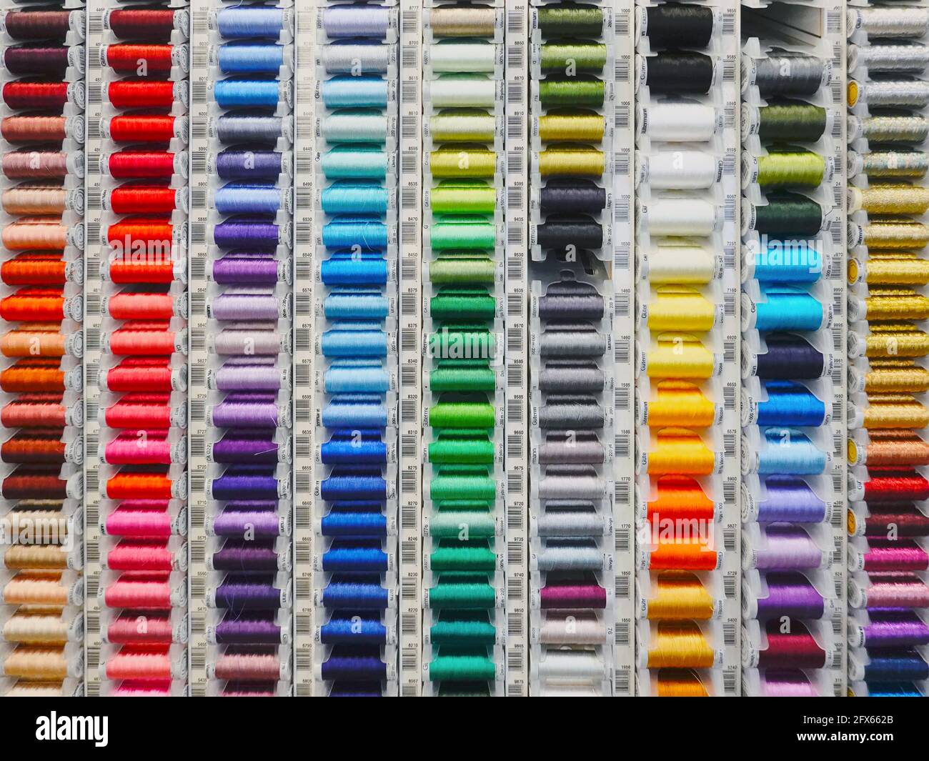 Un rack di bobine colorate di filo Viscosa 100% per la vendita in un negozio di tessuti, Coquitlam, B. C., Canada. Foto Stock