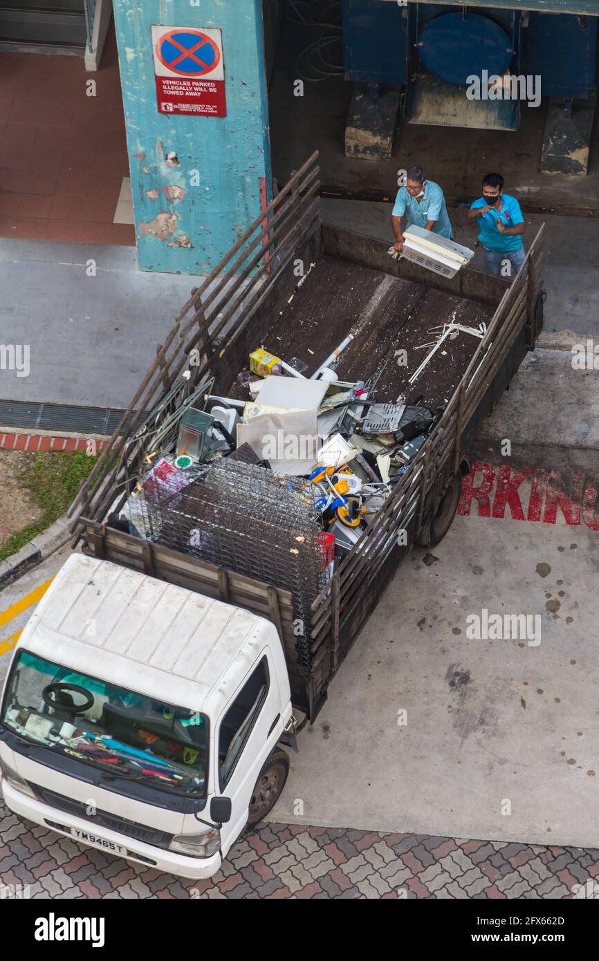 Vista aerea di 2 lavoratori indiani stanno gettando oggetti di plastica domestica indesiderati dall'area dello scivolo rifiuti sul camion. Singapore Foto Stock