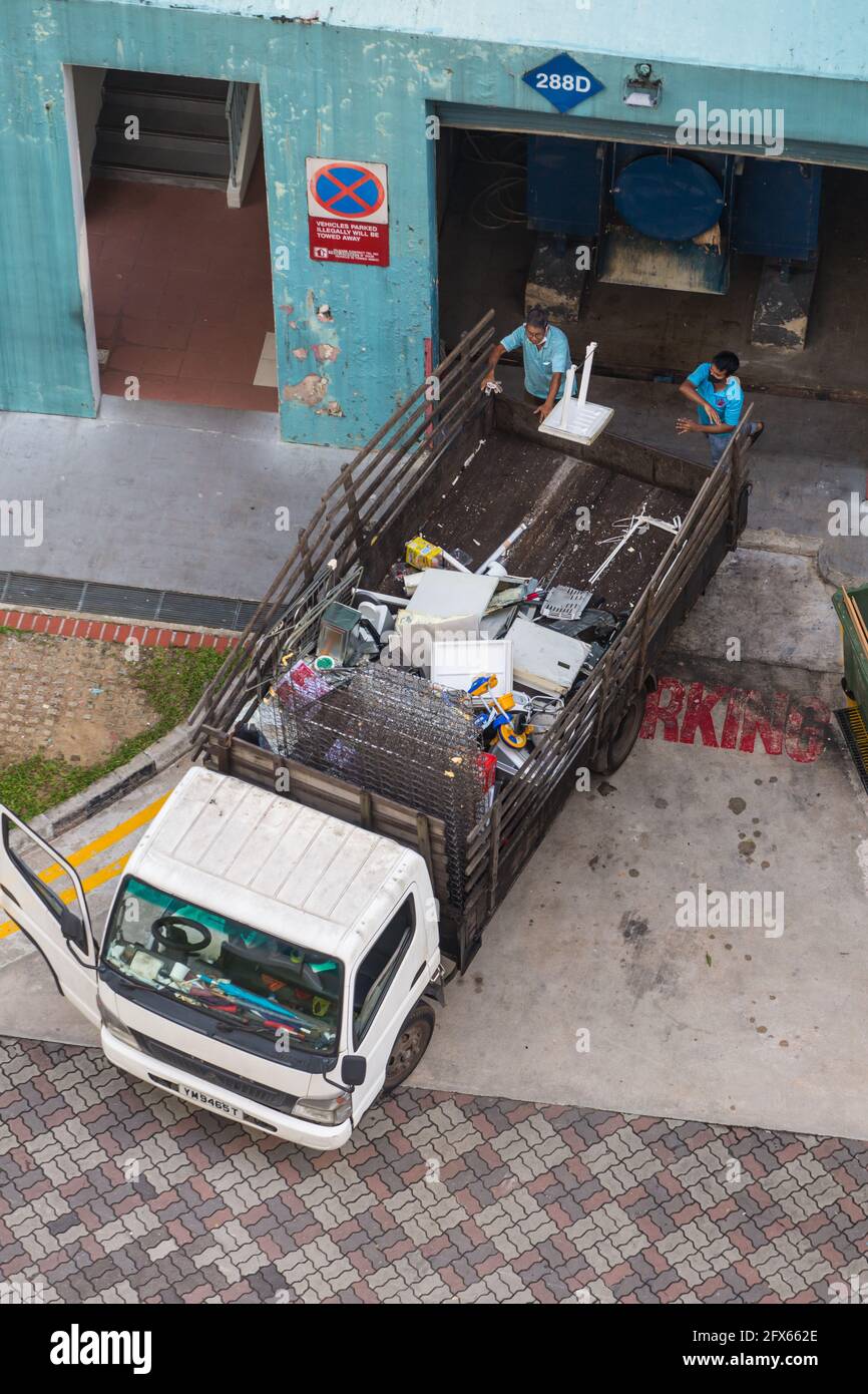 La vista aerea di due lavoratori sta gettando articoli di plastica usati per uso domestico dal luogo di tenuta dello scivolo per rifiuti nel carrello. Singapore Foto Stock