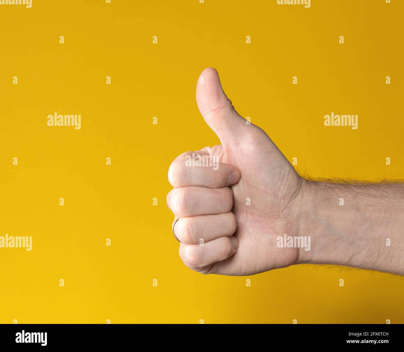 Mano dell'uomo con il pollice in alto isolato su sfondo giallo. Mostra come, segno positivo. Simbolo, icona di perfetto o Accetta. Foto Stock