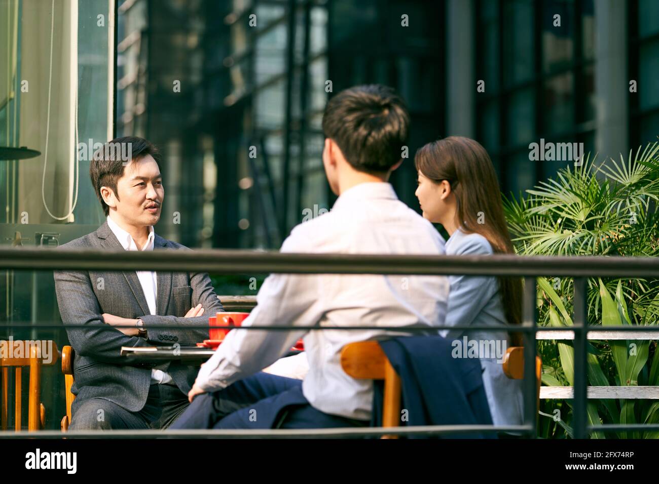 tre imprenditori asiatici che discutono di affari all'aperto in caffè colpo Foto Stock