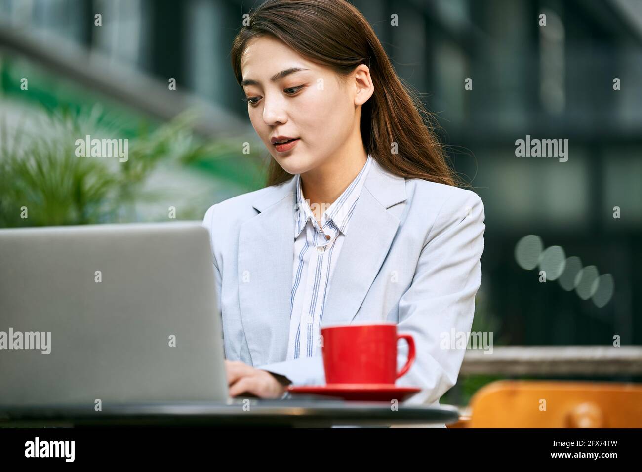 giovane donna d'affari asiatica che lavora all'aperto in una caffetteria utilizzando un computer portatile computer Foto Stock