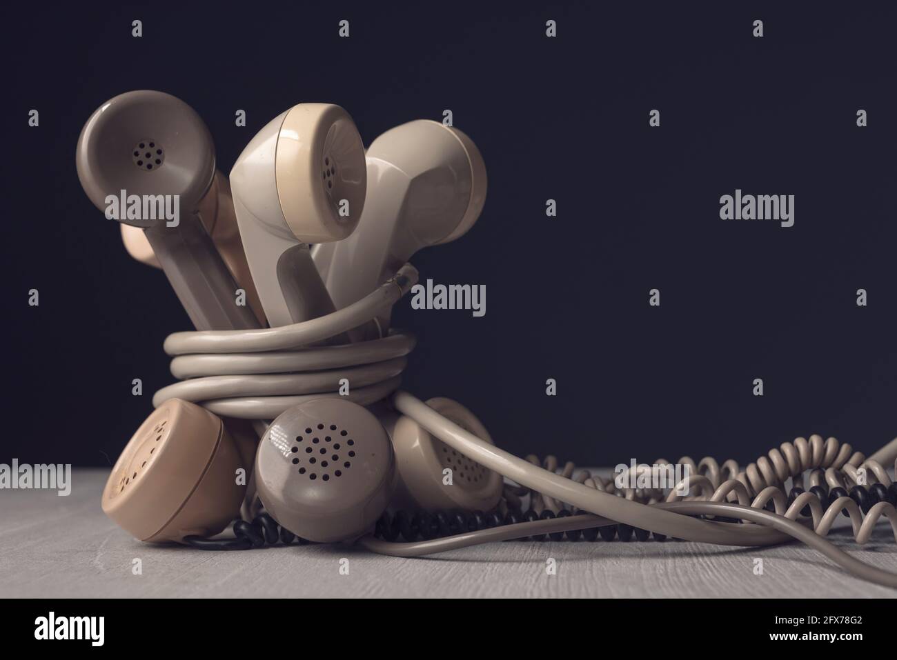 Vecchi ricevitori telefonici legati insieme su una scrivania, concetto di linee telefoniche inceppate Foto Stock