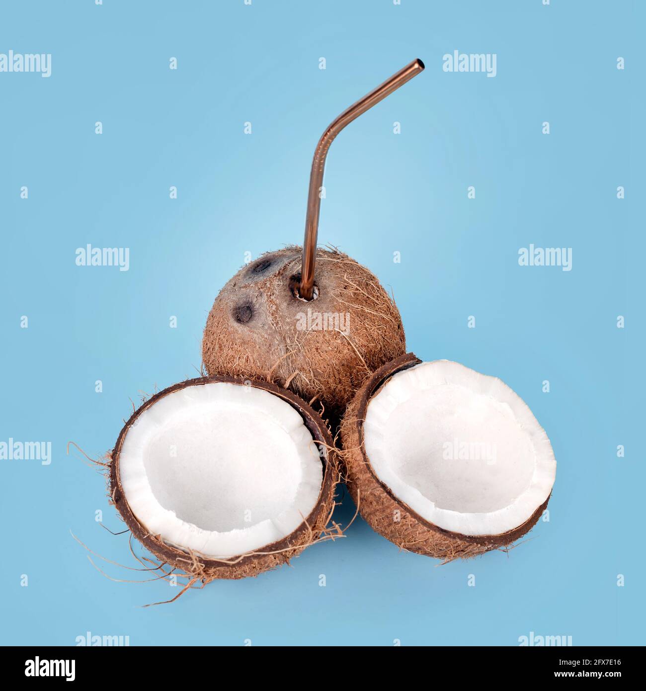 Aprire il cocco con la paglia su sfondo blu. Bevanda tropicale, vacanza estiva concetto creativo minimo. Frutta di cocco croccata con latte di cocco all'interno. Foto Stock
