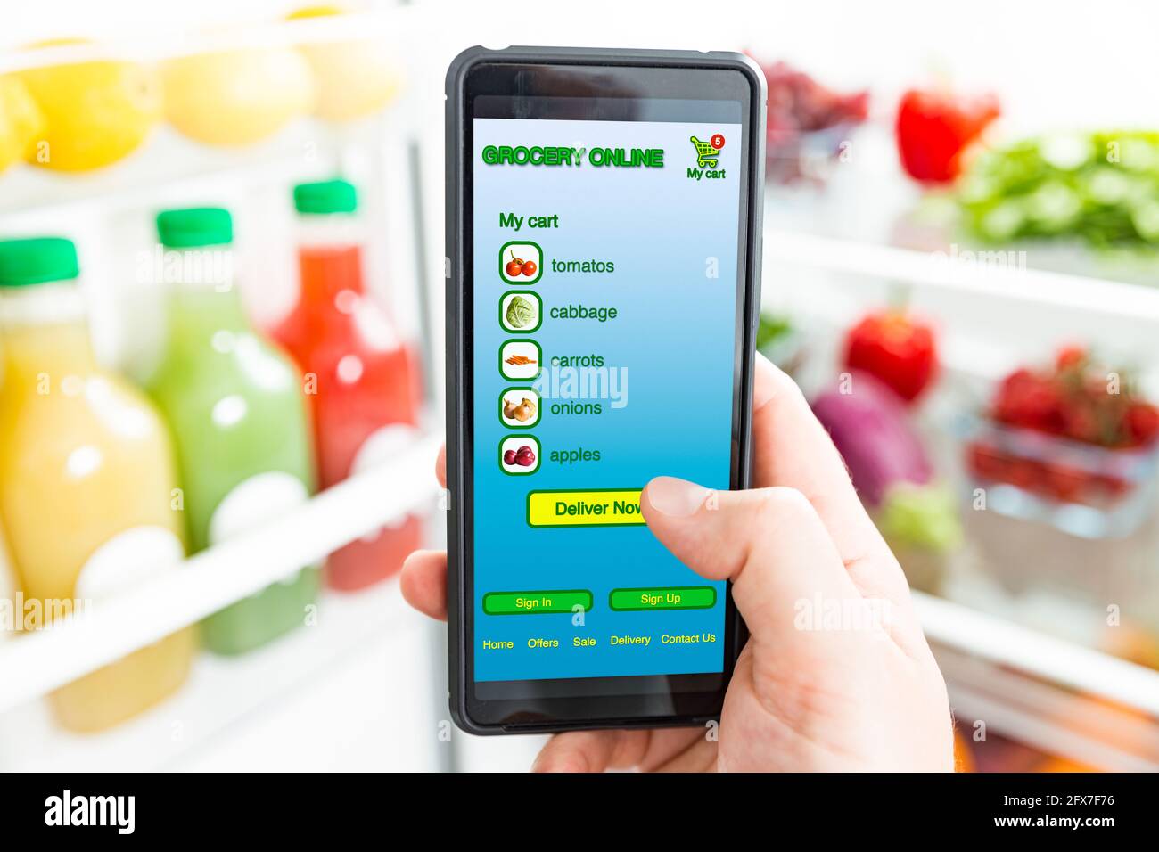Uomo che usa lo smartphone, che acquista cibo. Primo piano con il telefono. Acquisto di generi alimentari online. App mobile del negozio online di alimentari. Verdure fresche in frigorifero Foto Stock