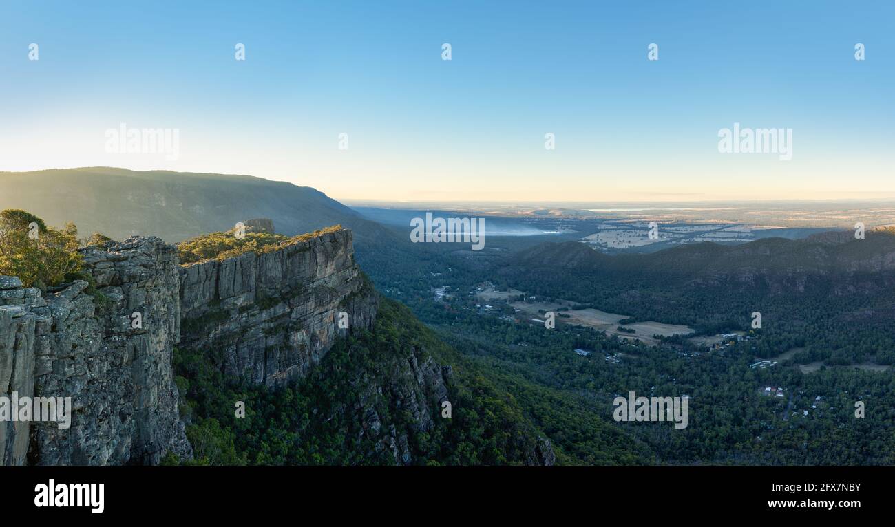 Una vista panoramica da un punto panoramico dei Grampians a una sporgenza rocciosa e nella valle di Halls Gap a Victoria con incendi che bruciano la schiena che fumano in lontananza. Foto Stock