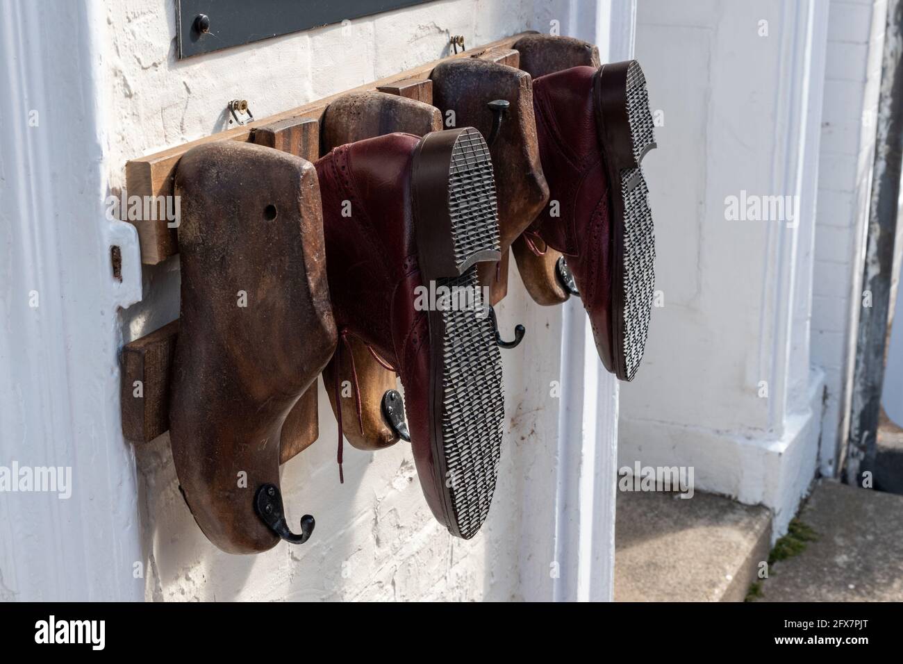 Le vecchie scarpe di legno si trasformano in un espositore all'esterno di un negozio di riparazione scarpe, High Street, Stony Stratford, UK Foto Stock