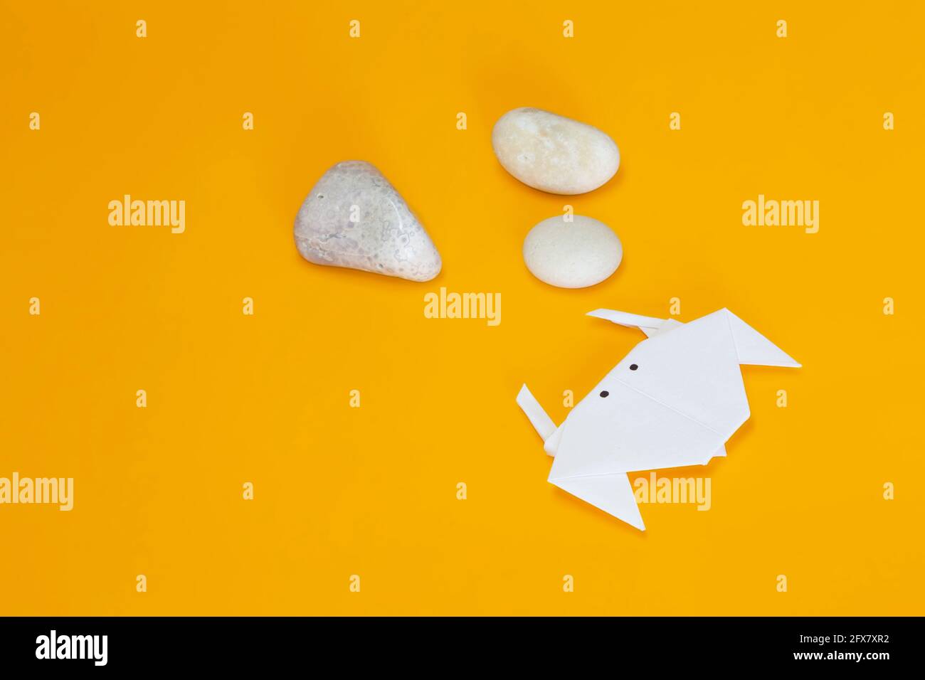 Animale acquatico fatto a mano con tecnica origami con occhi dipinti su una superficie gialla. C'è spazio libero nell'immagine. Accanto al granchio c'è un Foto Stock