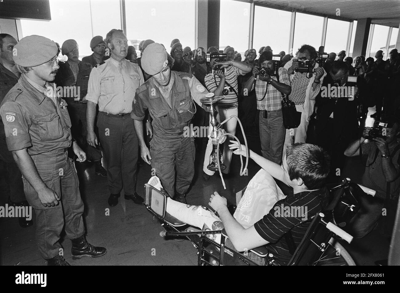 Arrivo a Schiphol di soldati dimessi, un soldato offre un dono a una persona con gamba in gesso, 26 luglio 1979, regali, militari, Peacekepers, Paesi Bassi, foto agenzia stampa del XX secolo, notizie da ricordare, documentario, fotografia storica 1945-1990, storie visive, Storia umana del XX secolo, che cattura momenti nel tempo Foto Stock