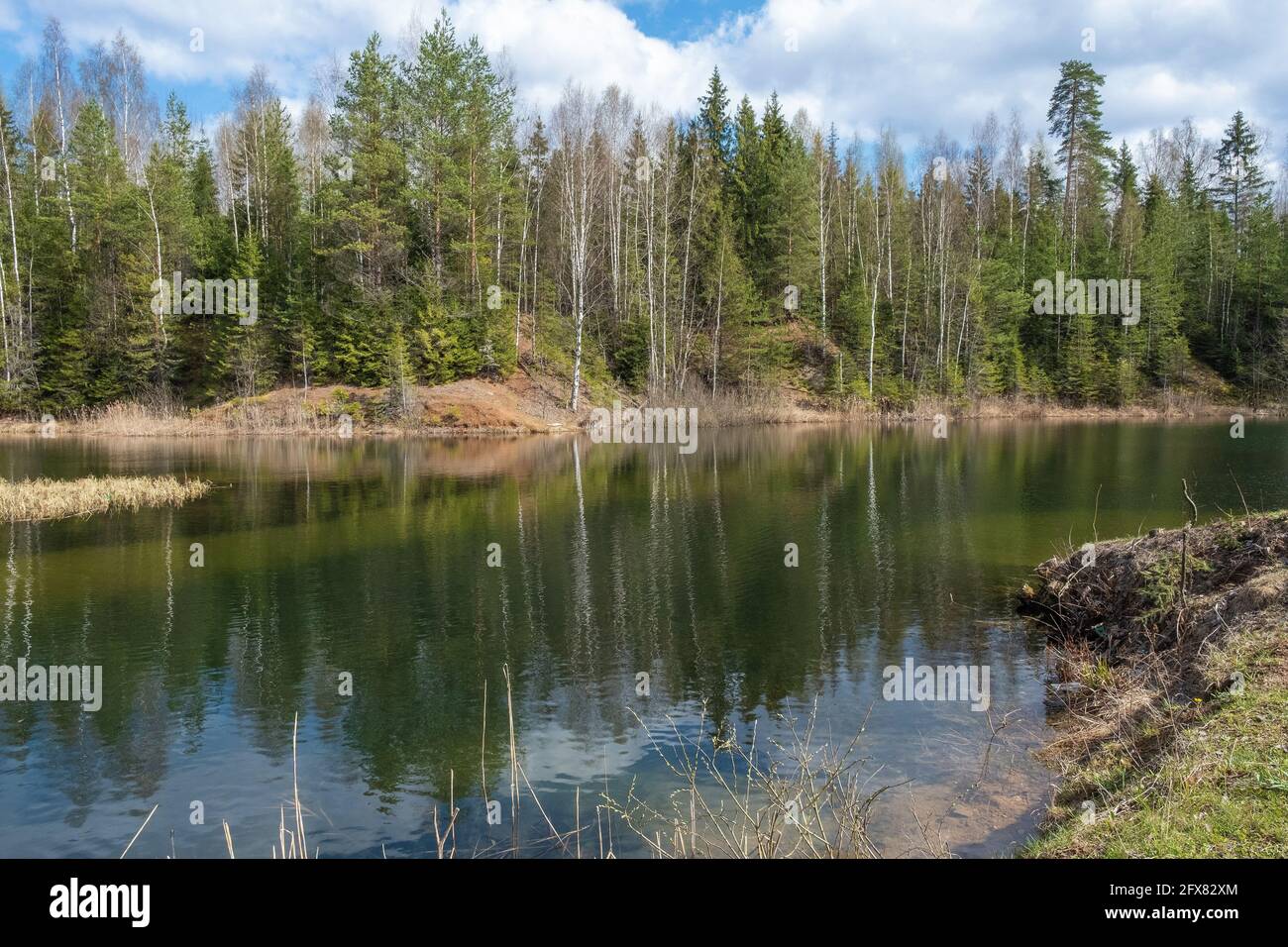 Piccolo lago con alte rive ripide in una soleggiata giornata di primavera, la Russia. Foto Stock