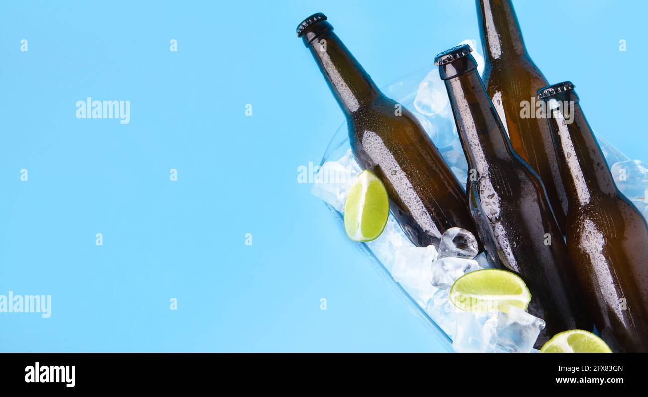 Festa rinfrescante drink per la compagnia. Bottiglie in vetro scuro con birra o lager senza etichette con gocce fluenti Foto Stock