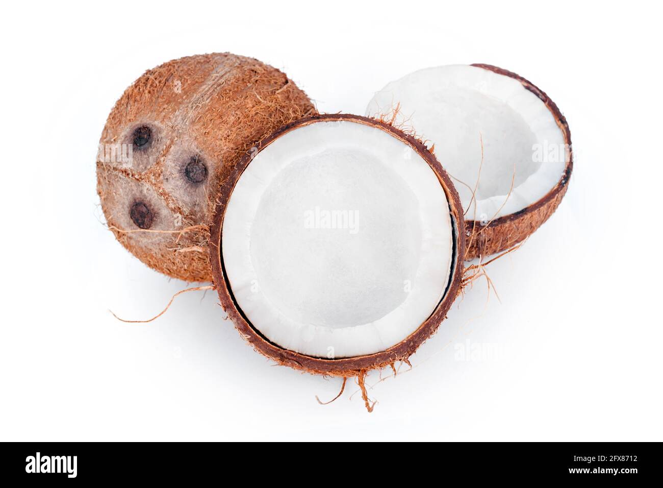 Noci di cocco intere e incrinate isolate su sfondo bianco. Frutta di cocco sbucciata che mostra i tre pori caratteristici. Tagliare a metà la chiocciola di cocco. Foto Stock