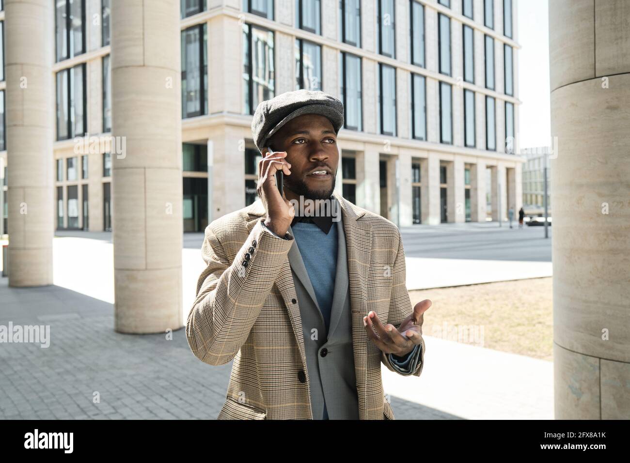 Giovane africano che parla sul telefono cellulare mentre si è in piedi la città Foto Stock