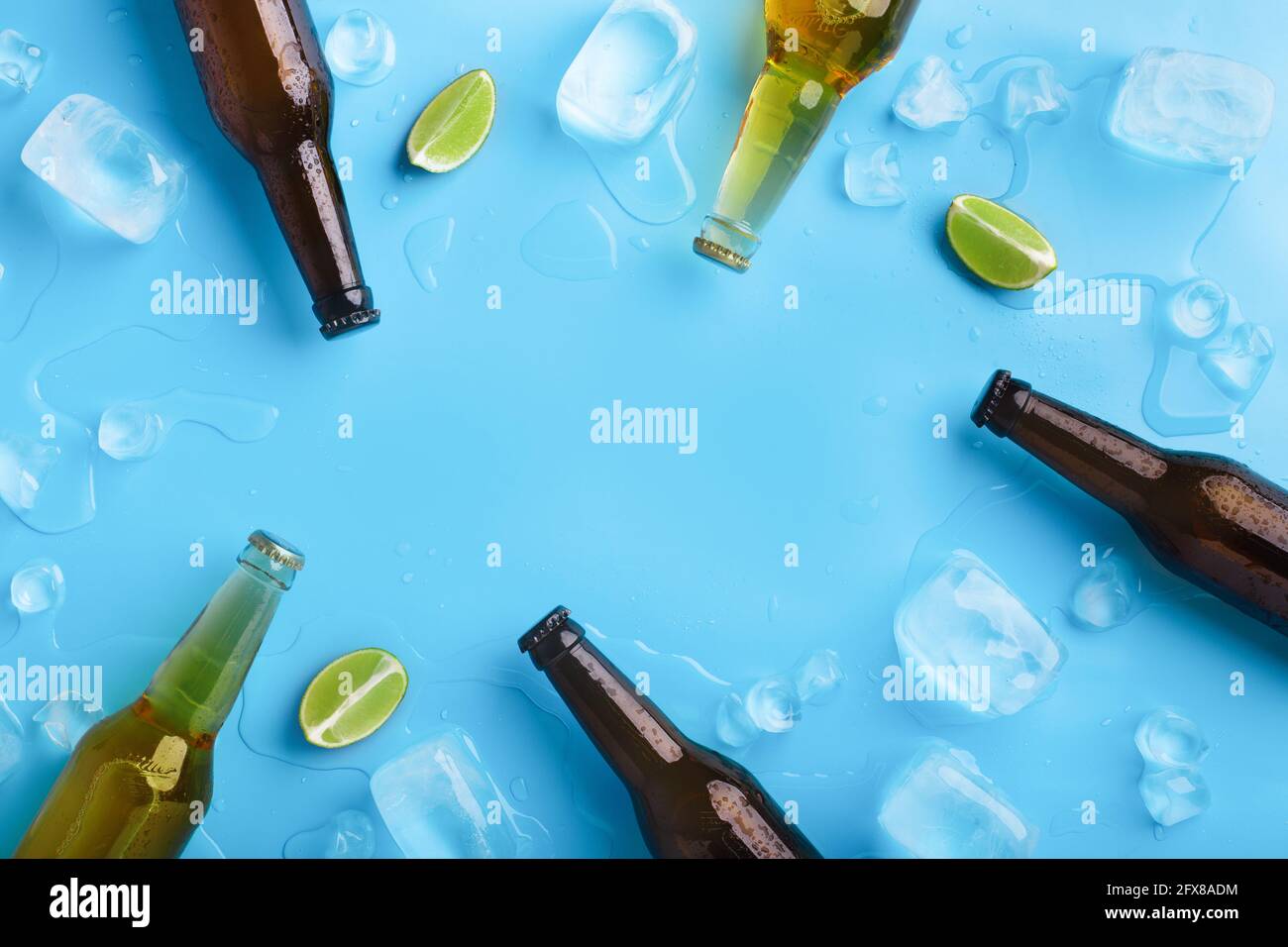 Bottiglie in vetro trasparente e scuro con birra, senza etichette, con gocce fluenti, giacciono con ghiaccio e calce Foto Stock
