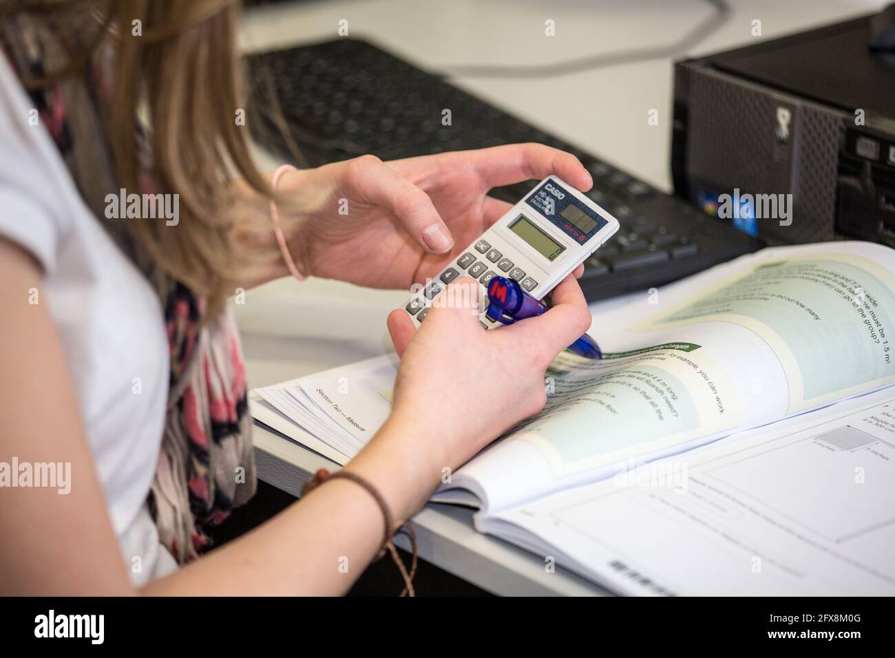 Londra, UK - CIRCA 2014 marzo - una donna caucasica che usa una calcolatrice mentre risolve i problemi di matematica Foto Stock