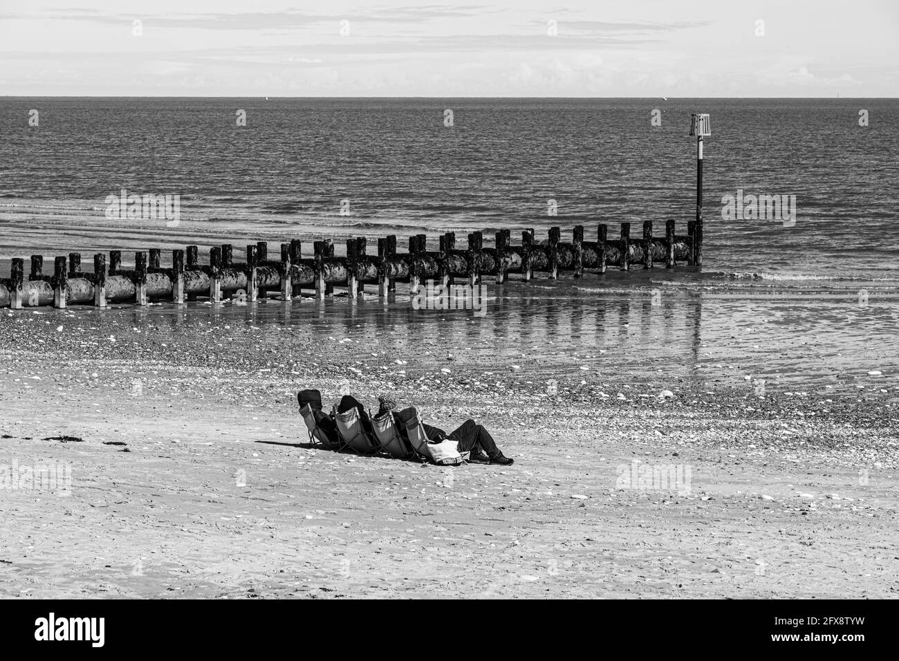Quattro persone che prendono il sole a metà aprile accanto al Mare del Nord a Bridlington, East Riding dello Yorkshire, Inghilterra Regno Unito. Versione a colori 2FX8W2A. Foto Stock