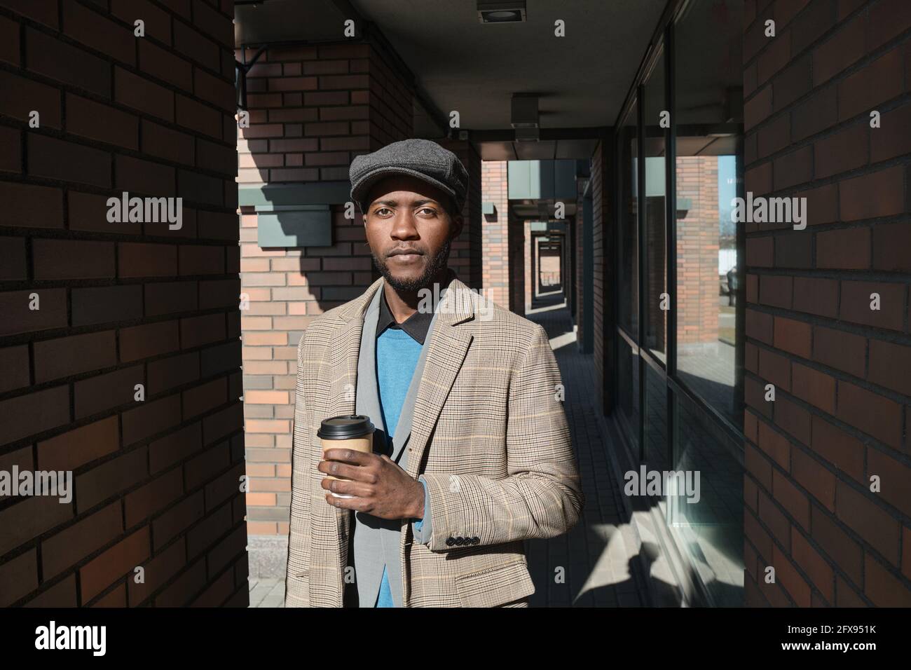Ritratto della città africana residente tenendo una tazza di caffè e. guardare la fotocamera mentre si è in piedi all'aperto Foto Stock