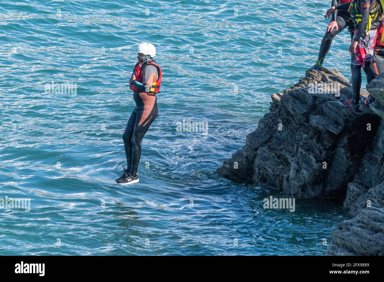 I vacanzieri saltano dalle rocce costellando con una guida su Towan Head a Newquay in Cornovaglia. Foto Stock