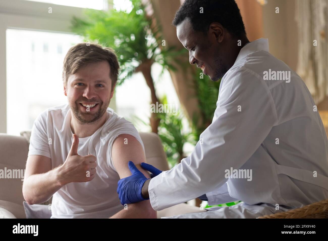 Medico africano che fa iniezione di vaccino a pazienti di sesso maschile Foto Stock