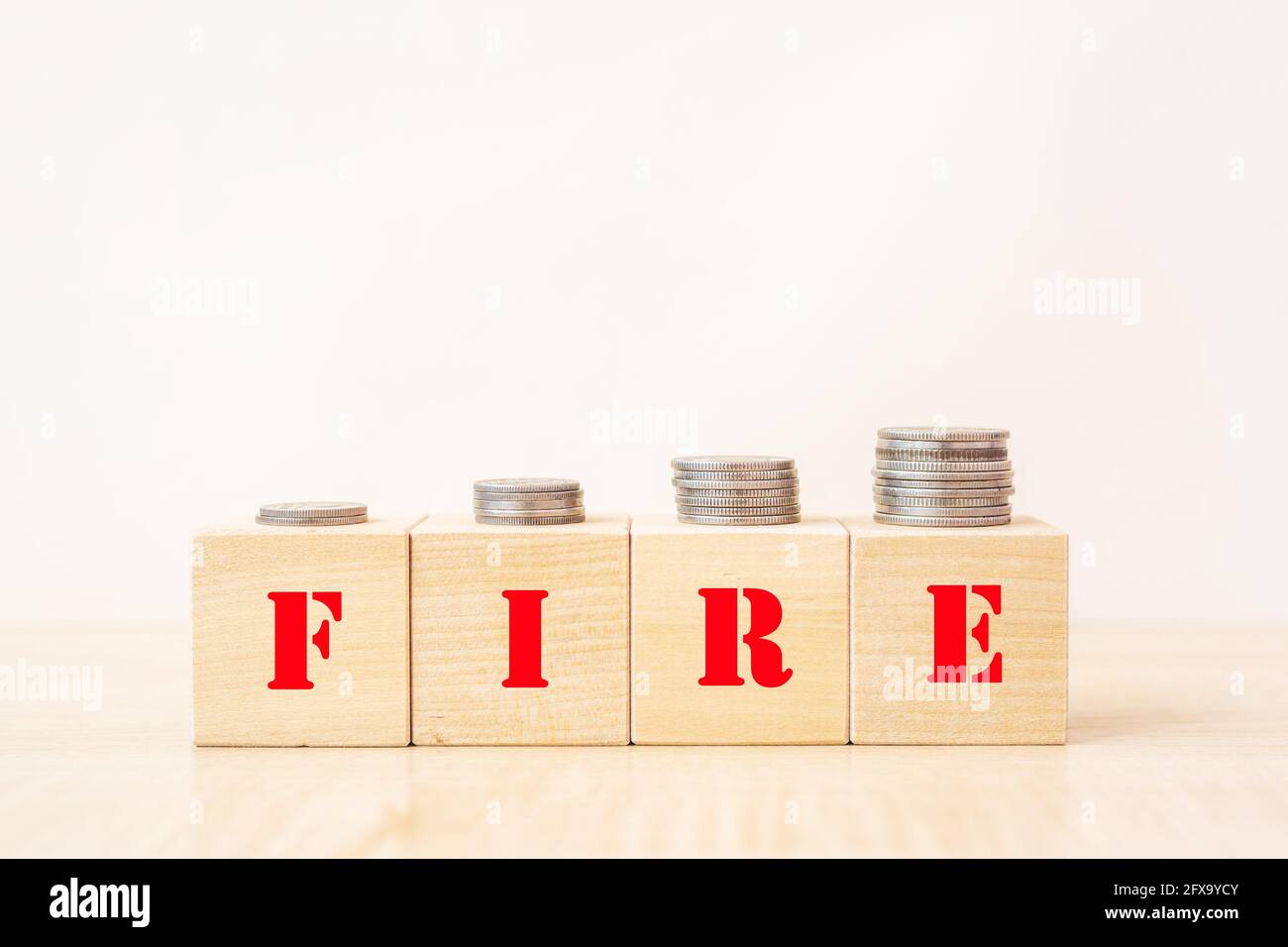 Monete di denaro su blocchi di legno con fuoco di testo - finanziario l'indipendenza si ritanca presto Foto Stock