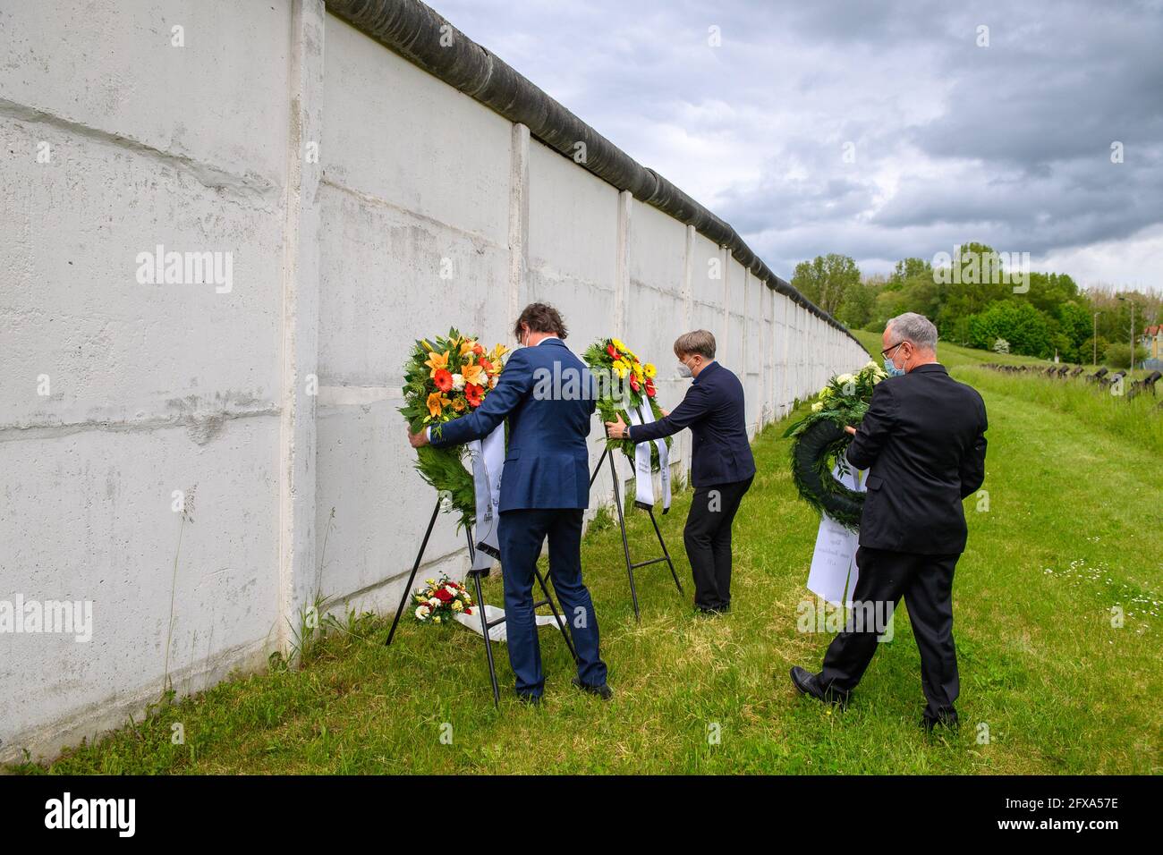 26 maggio 2021, Sassonia-Anhalt, Hötensleben: René Müller, presidente della Hötensleben Border Monument Association (l-r), Kai Langer, direttore della Saxony-Anhalt Memorial Foundation e Henning Konrad otto dell'associazione 'Grenzenlos - Wege zum Nachbarn' (Borderless - sentieri per i vicini) e il primo consigliere comunale di Helmstedt posero le corone al monumento di confine. La cerimonia di deposizione della corona si è svolta nel 69° anniversario dell'istituzione del regime di frontiera della RDT e dei relativi reinsediamento forzato dall'area ristretta. Il 26 maggio 1952 è stato emesso un ordine di polizia che stabiliva un 5-K. Foto Stock