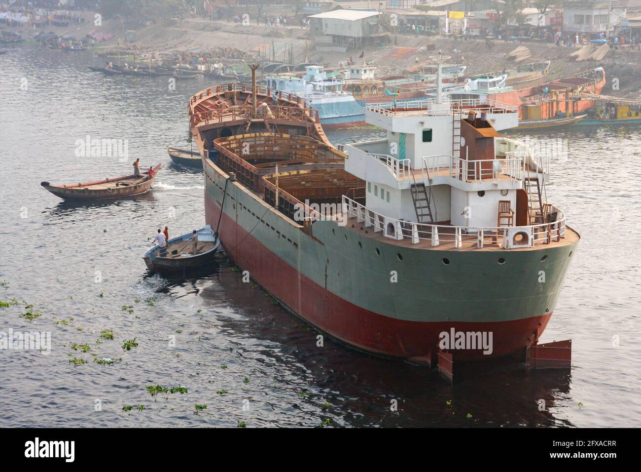 DHAKA, BANGLADESH - DICEMBRE 2011: Una piccola barca guida una grande nave verso il fiume del Buriganga. Foto Stock