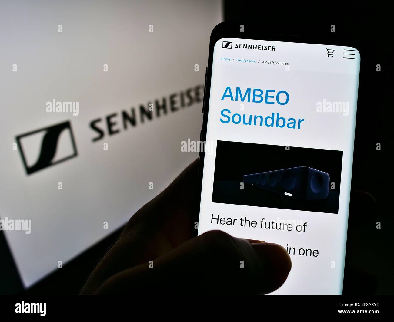 Persona titolare cellulare con pagina web della società audio tedesca Sennheiser electronic GmbH Co KG su schermo con logo. Mettere a fuoco il centro del display del telefono. Foto Stock