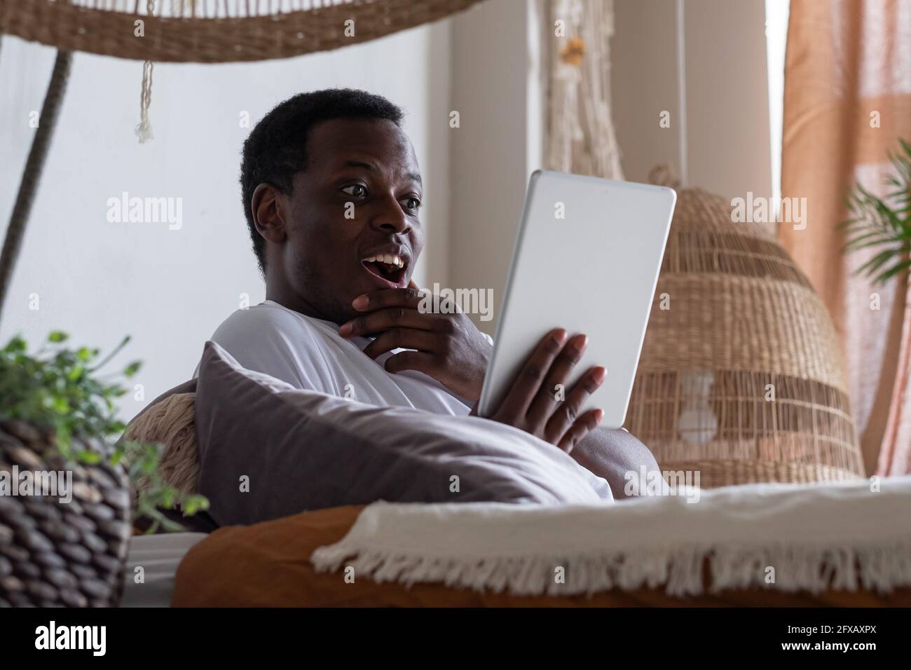 Sorridente uomo web surfing informazioni a casa. Foto Stock