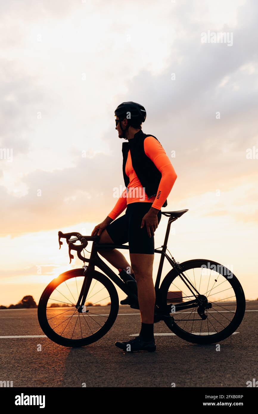 Uomo atletico seduto in bicicletta e godendo il tramonto Foto Stock